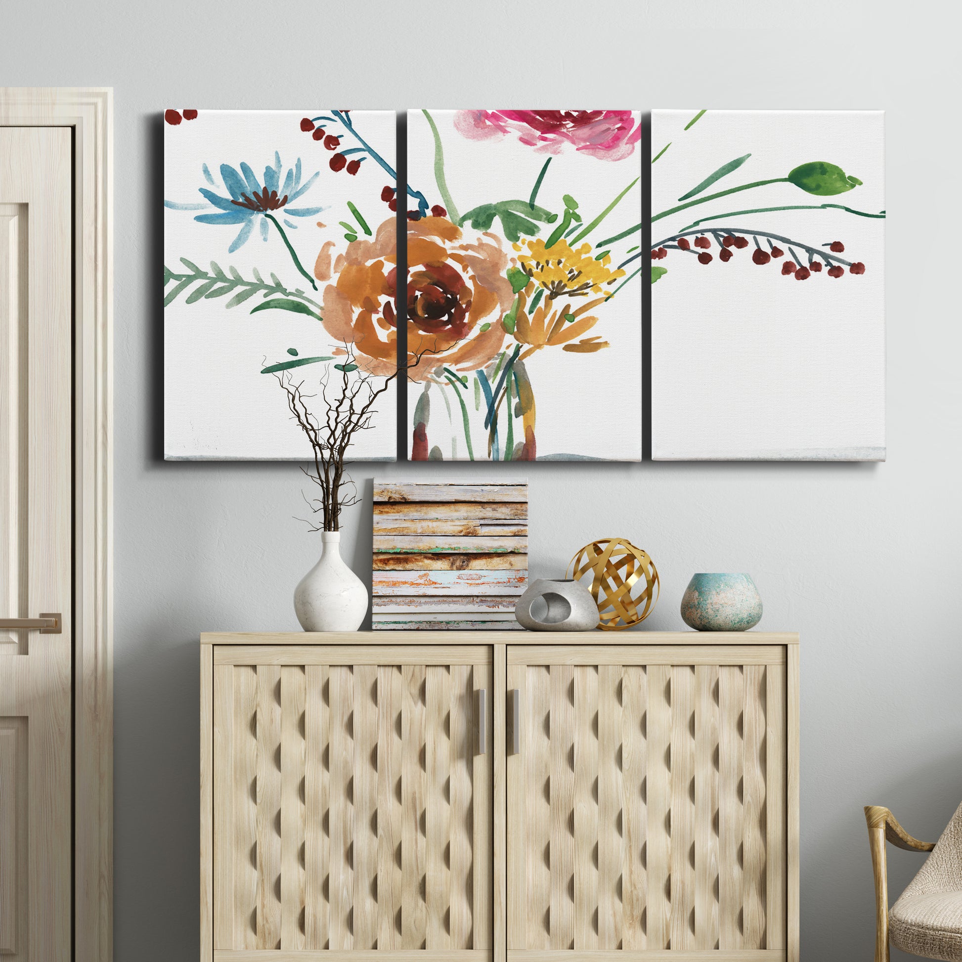 Three-panel canvas wall art featuring vibrant floral bouquet, displayed above a cabinet in an entryway.