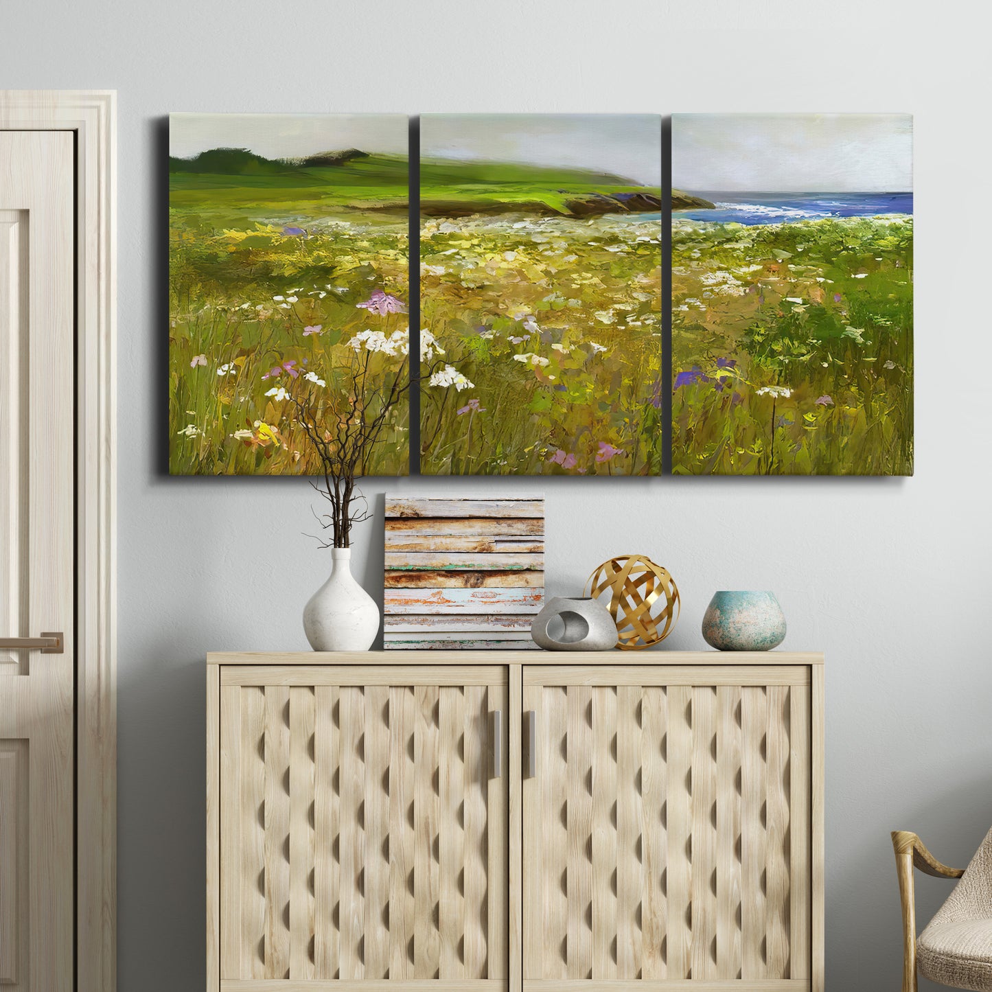 Three-panel canvas wall art featuring rugged coastal cliff landscape, displayed above a cabinet in an entryway.