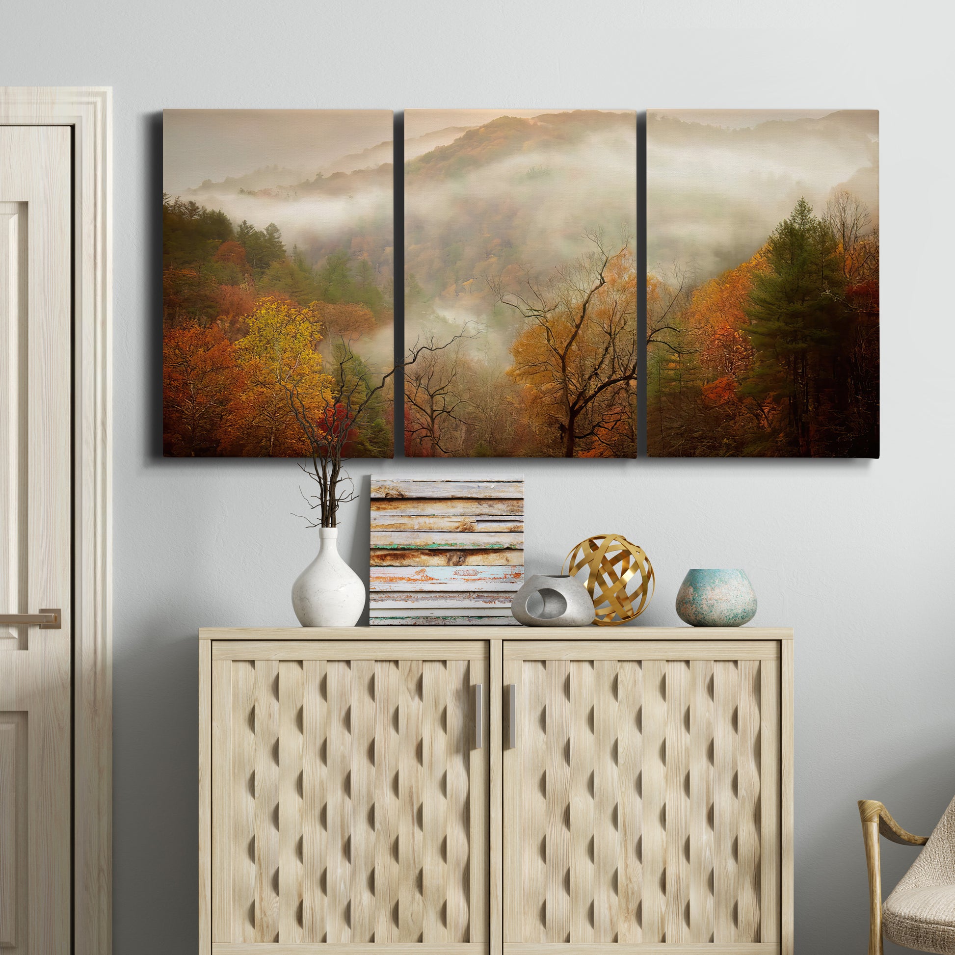 Three-panel canvas wall art featuring misty autumn landscape photograph, displayed above a cabinet in an entryway.