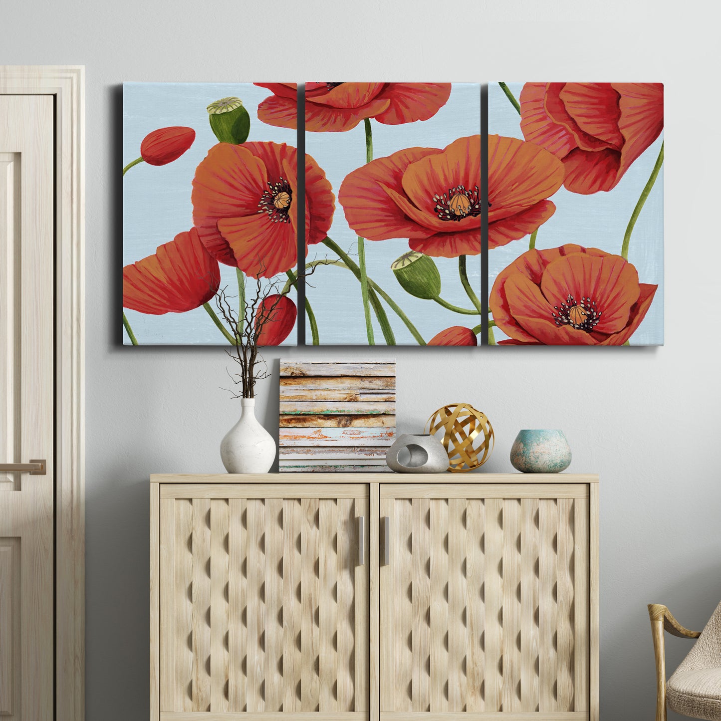 Three-panel canvas wall art featuring red poppies in motion, displayed above a cabinet in an entryway.