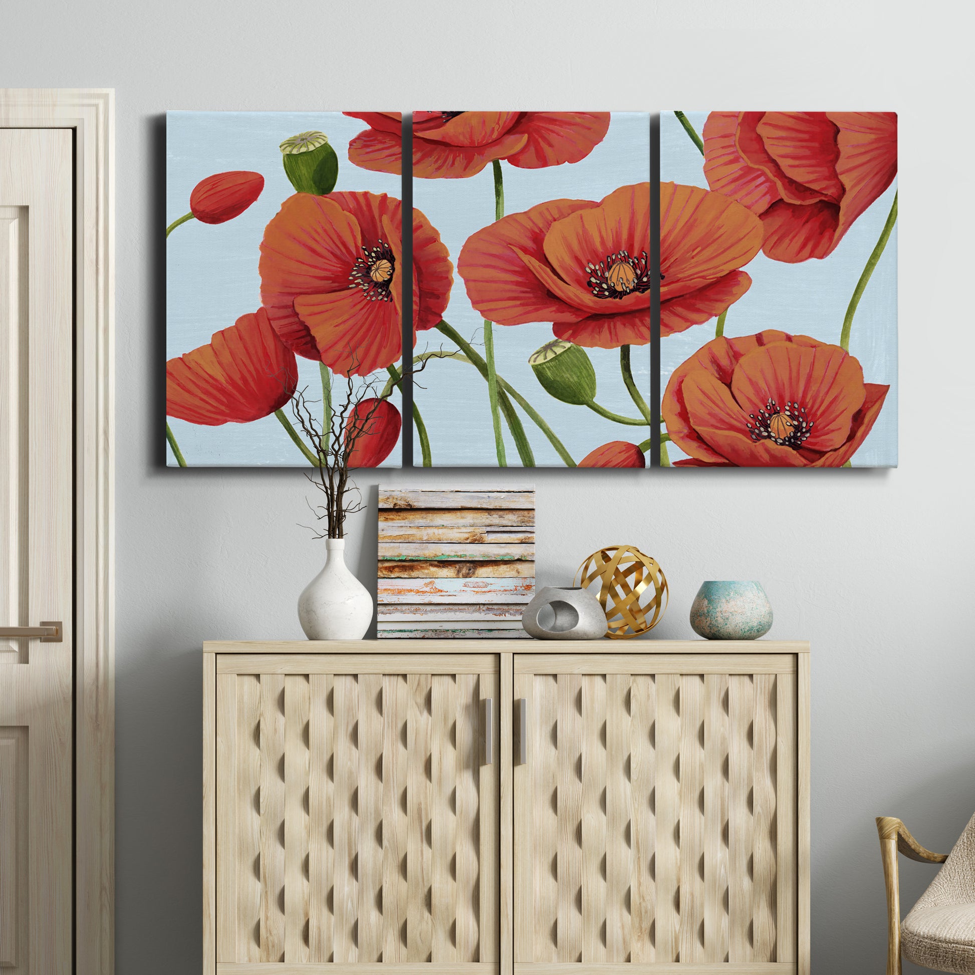 Three-panel canvas wall art featuring red poppies in motion, displayed above a cabinet in an entryway.