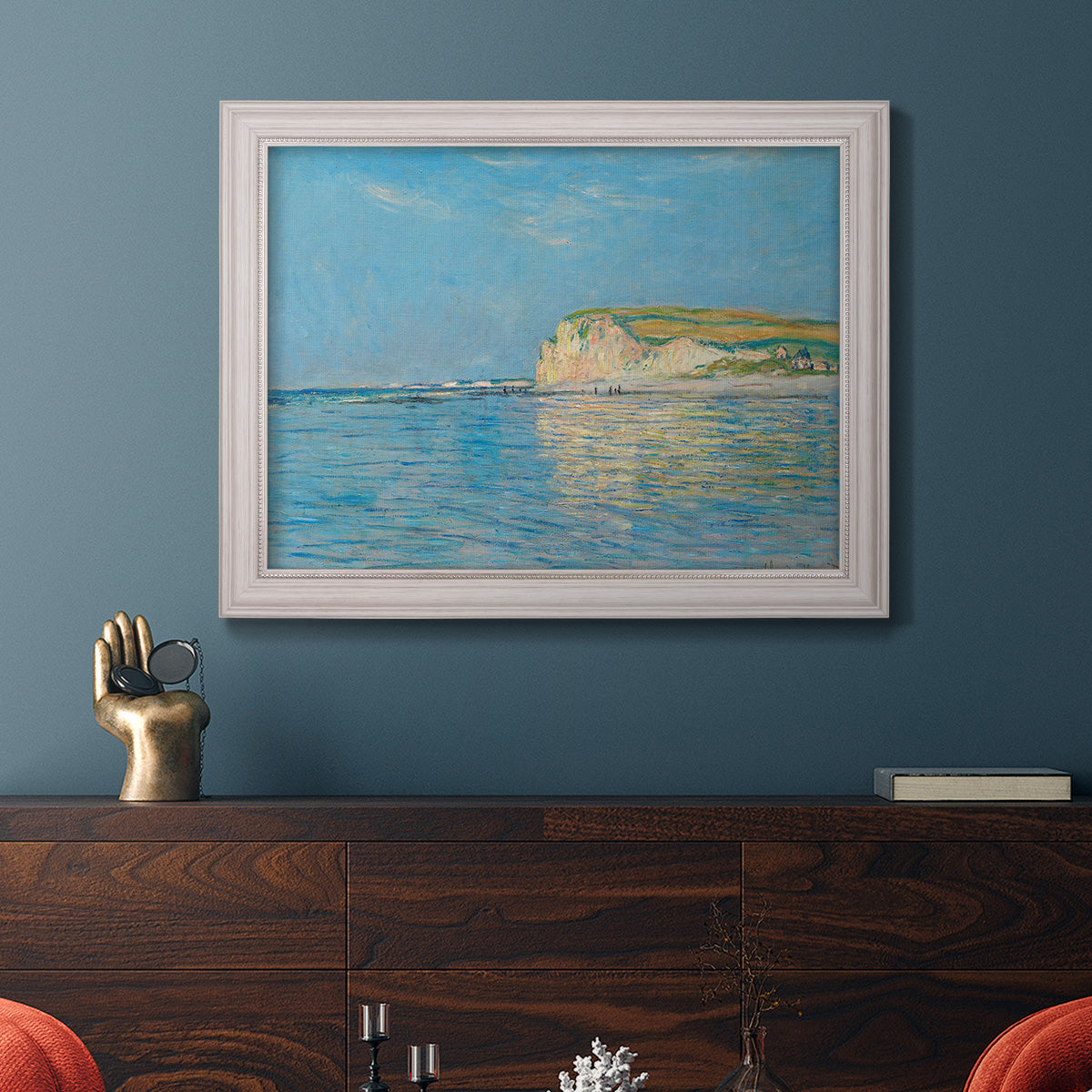Impressionist coastal low-tide seascape at Pourville by Claude Monet in an ornate weathered white frame displayed in a dark-toned interior setting.