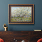 Impressionist white-blossomed orchard landscape by Vincent van Gogh in an ornate bronzed mahogany wood frame displayed in a dark-toned interior setting.