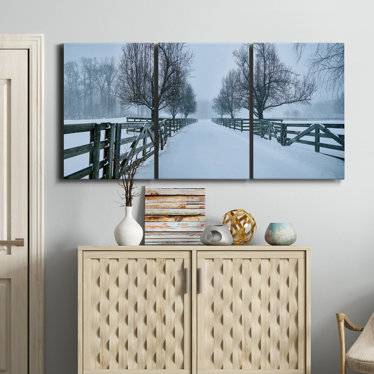 Three-panel canvas wall art featuring snow covered rural road photograph, displayed above a cabinet in an entryway.