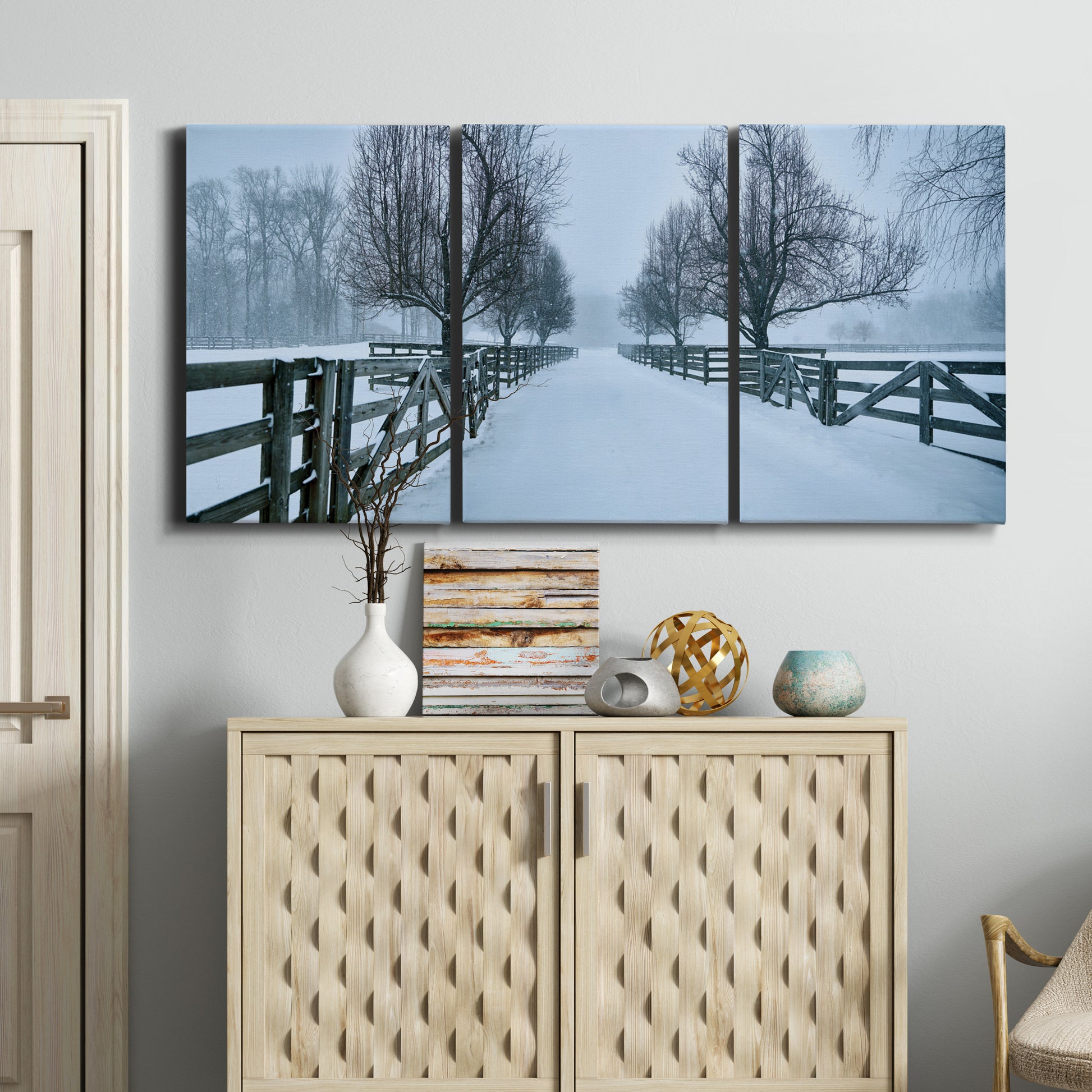 Three-panel canvas wall art featuring snow covered rural road photograph, displayed above a cabinet in an entryway.
