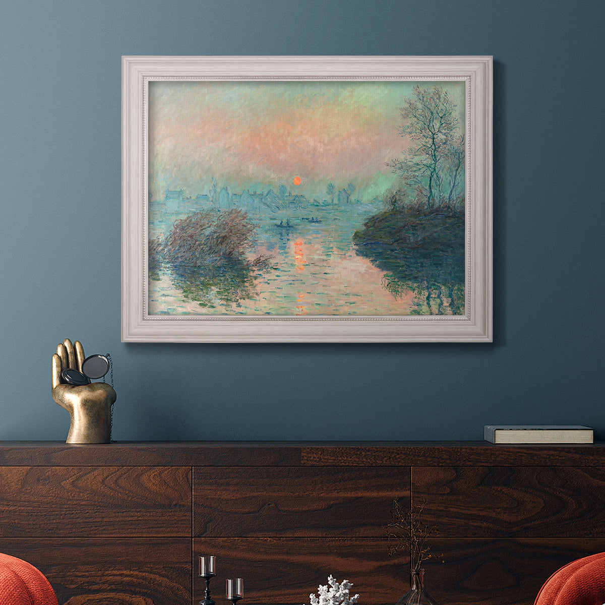 Impressionist winter river sunset scene by Claude Monet in an ornate weathered white frame displayed in a dark-toned interior setting.