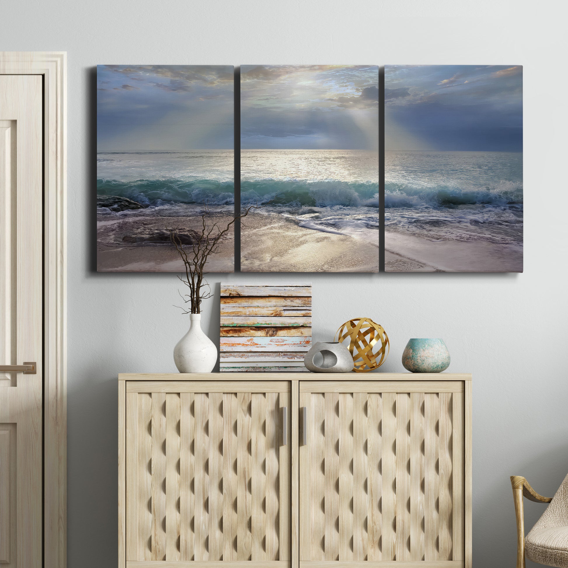 Three-panel canvas wall art featuring soft sunrise over open water, displayed above a cabinet in an entryway.
