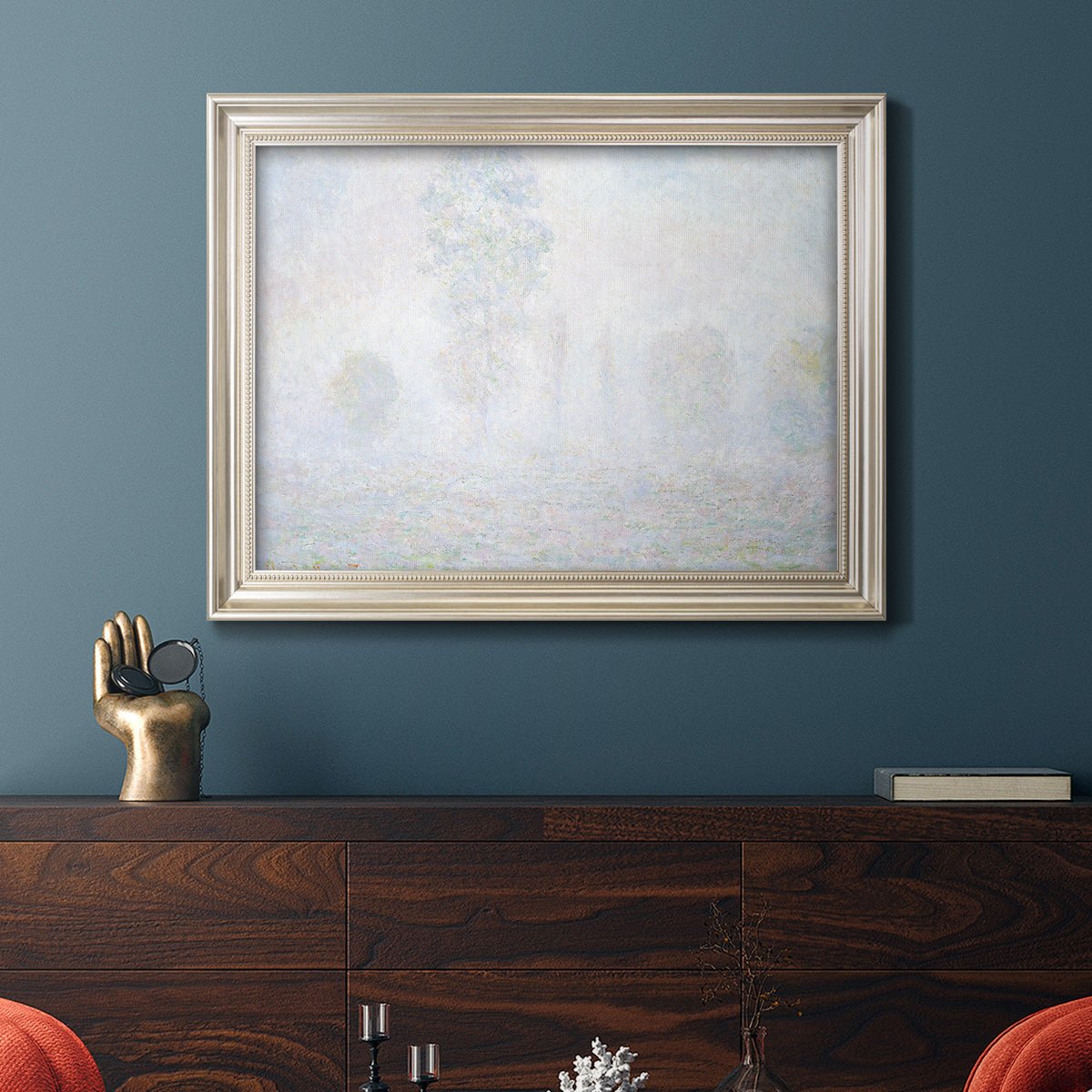 Impressionist atmospheric landscape in morning haze by Claude Monet in an ornate champagne frame displayed in a dark-toned interior setting.