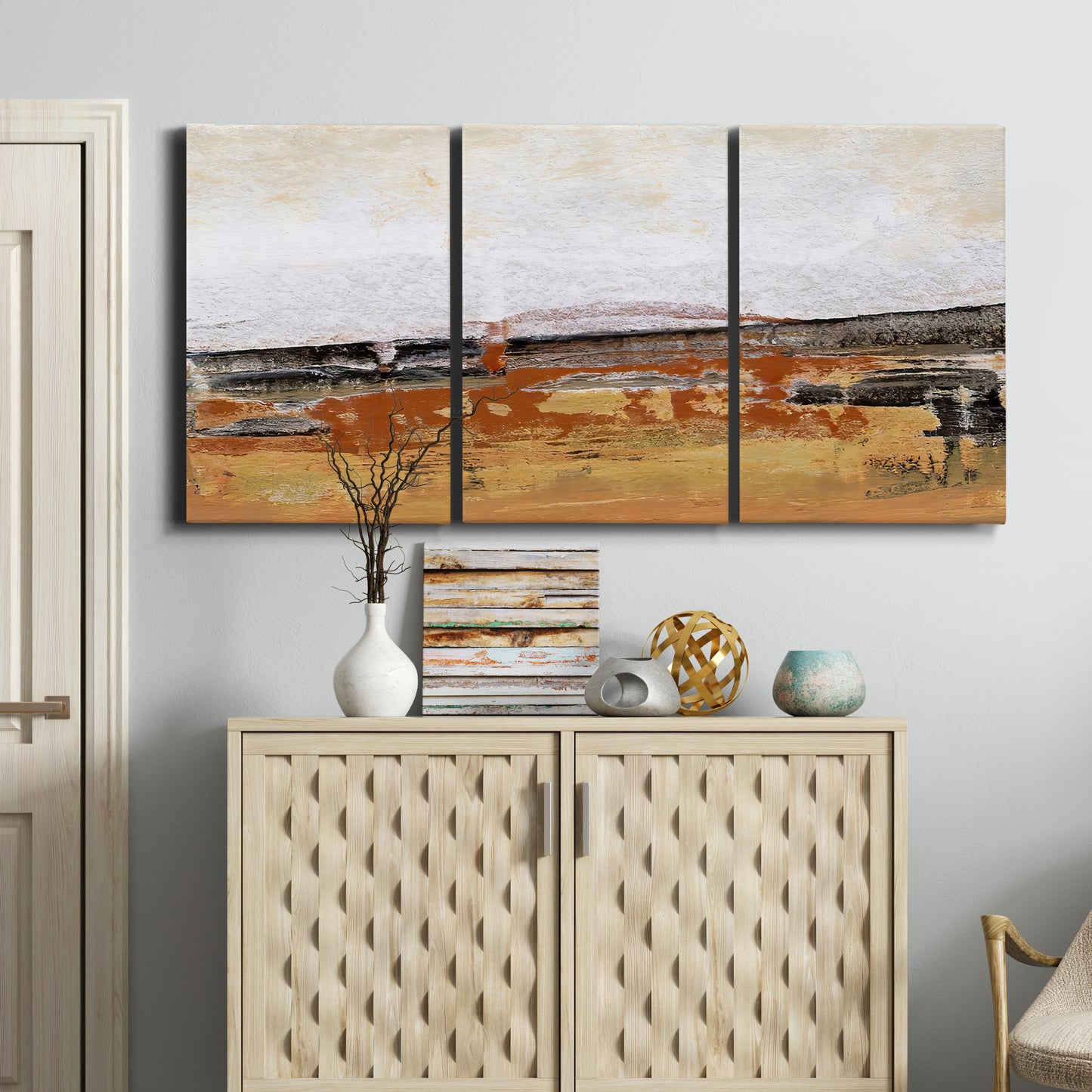 Three-panel canvas wall art featuring abstract bridge landscape in ochre, displayed above a cabinet in an entryway.