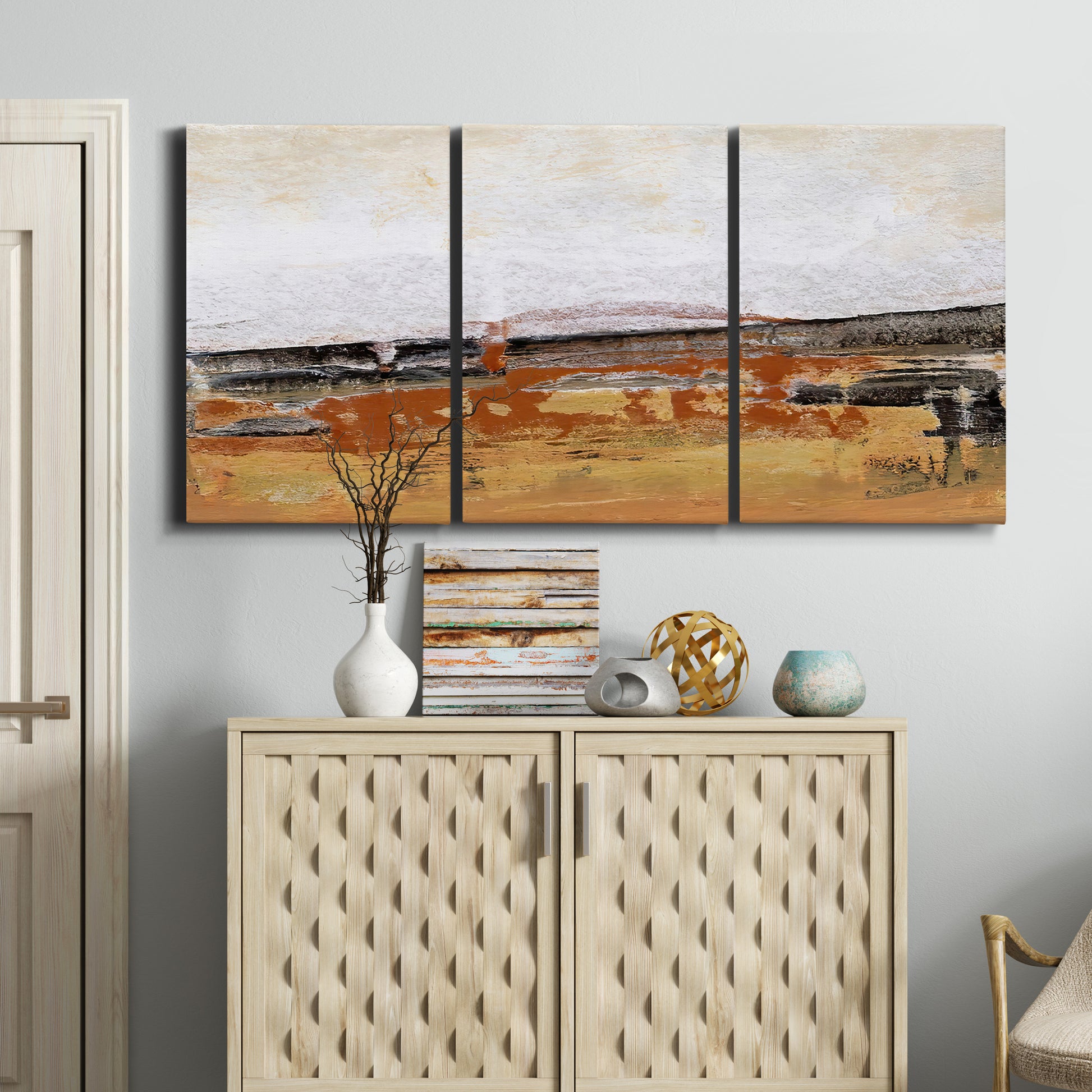 Three-panel canvas wall art featuring abstract bridge landscape in ochre, displayed above a cabinet in an entryway.