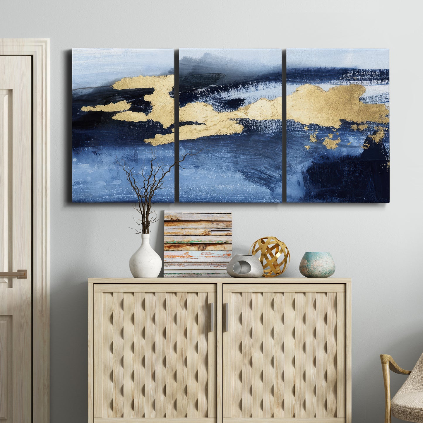 Three-panel canvas wall art featuring coastal shoreline with warm light, displayed above a cabinet in an entryway.