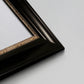 Detail of ornate black frame with gilded inner detail.