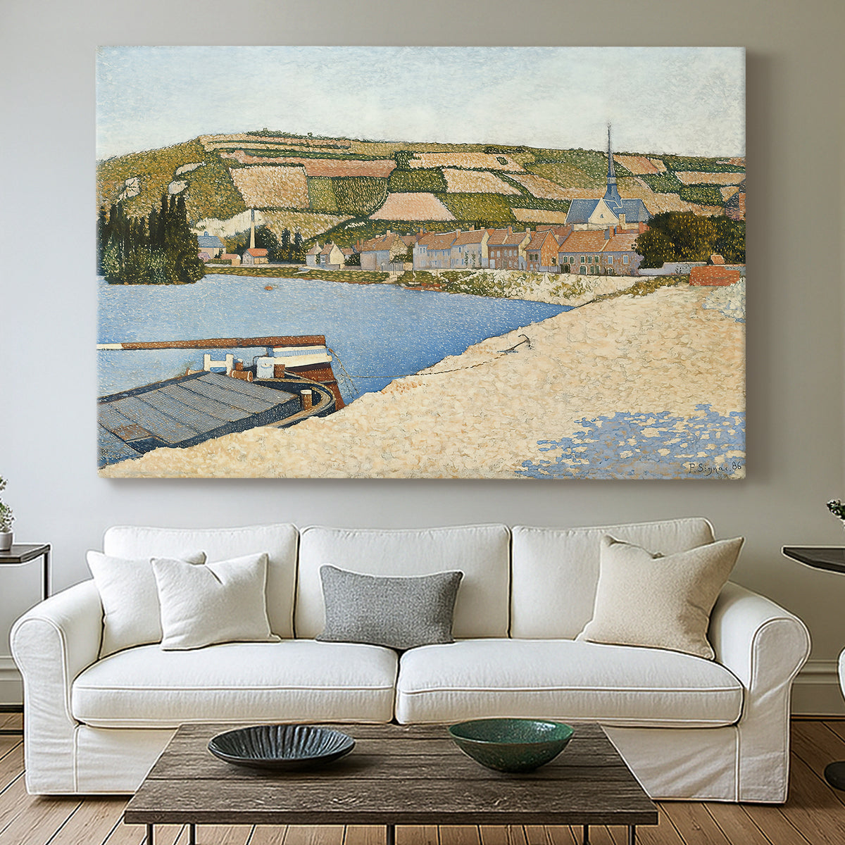 Canvas art print detailing a tranquil river composition with village, centered above a sofa as a large focal wall piece