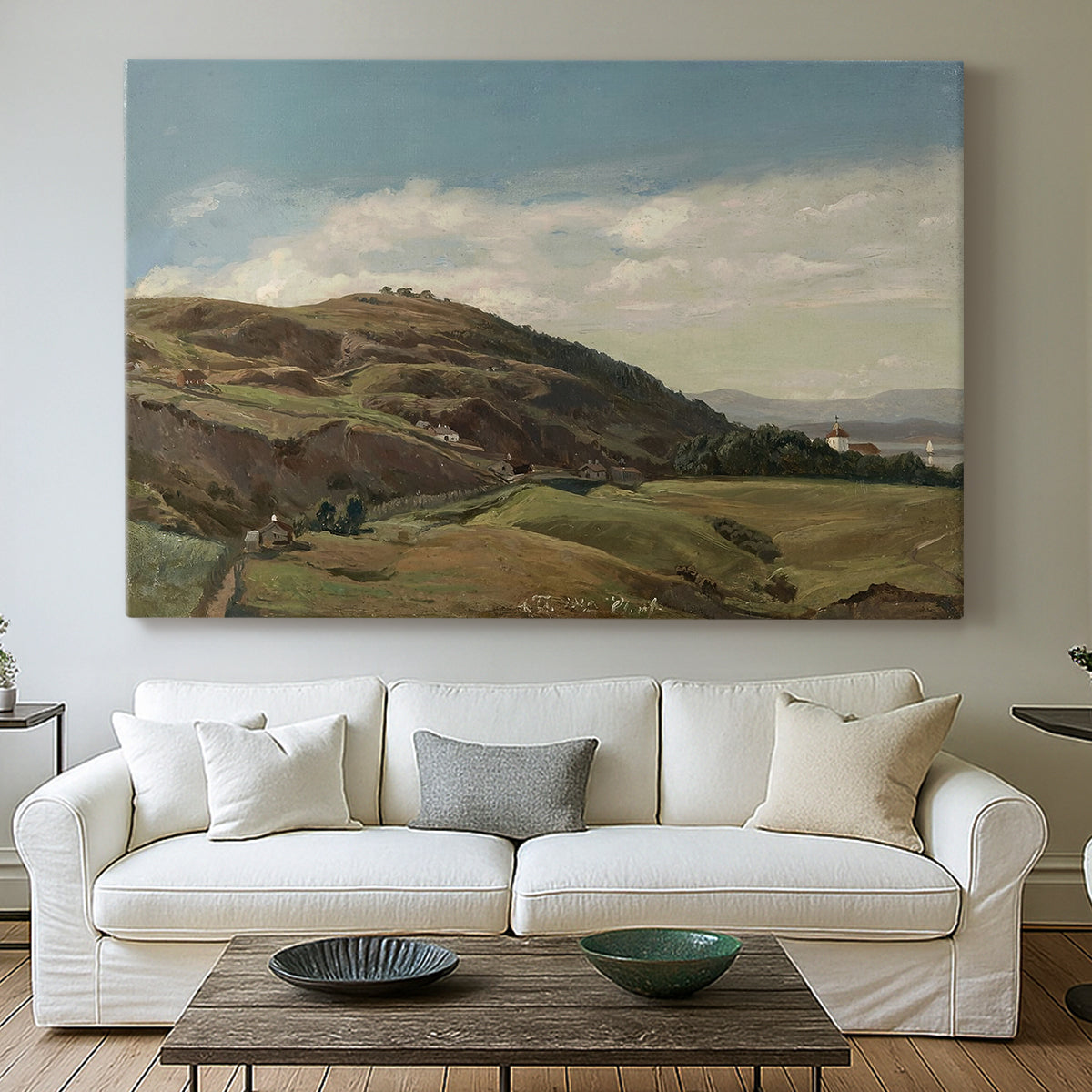 Canvas art print detailing a peaceful rural vista with greenery, water, and architectural landmark, centered above a sofa as a large focal wall piece