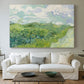 Canvas art print detailing a rural field view with textured brushwork and distant slopes, centered above a sofa as a large focal wall piece