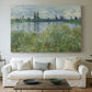 Canvas art print detailing a natural landscape with calm water and soft foliage, centered above a sofa as a large focal wall piece