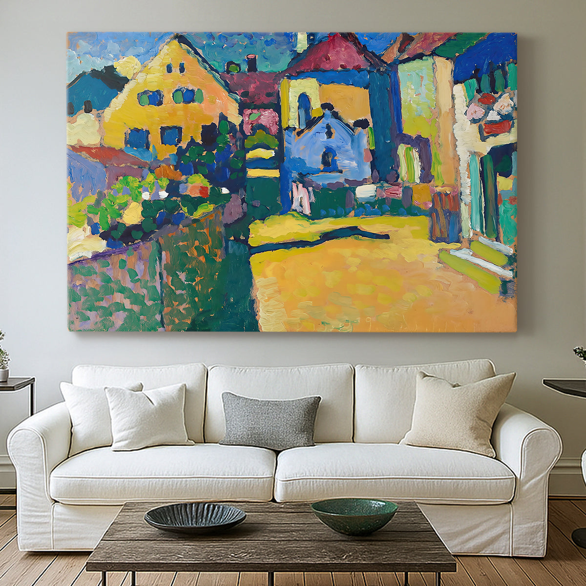 Canvas art print detailing a countryside street view with houses and greenery in vibrant tones, centered above a sofa as a large focal wall piece