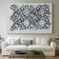 Canvas art print detailing a botanical pattern with fluid arrangement of flowers and foliage, centered above a sofa as a large focal wall piece