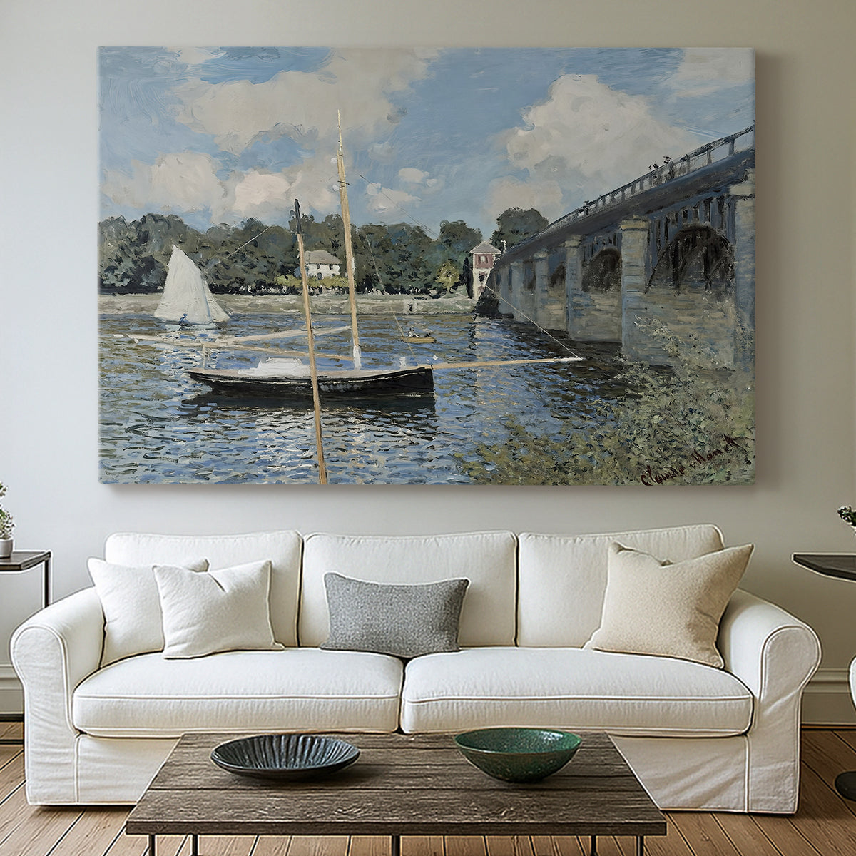 Canvas art print detailing a scenic riverscape with architecture and nautical activity, centered above a sofa as a large focal wall piece