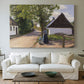 Canvas art print detailing a village setting with people and traditional architecture, centered above a sofa as a large focal wall piece