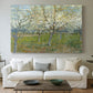 Canvas art print detailing a stylized orchard composition with delicate tones, centered above a sofa as a large focal wall piece