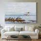 Canvas art print detailing a flock of geese positioned along marshy terrain, centered above a sofa as a large focal wall piece