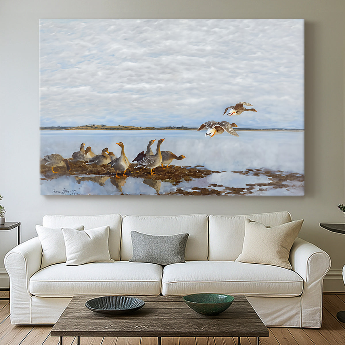 Canvas art print detailing a flock of geese positioned along marshy terrain, centered above a sofa as a large focal wall piece