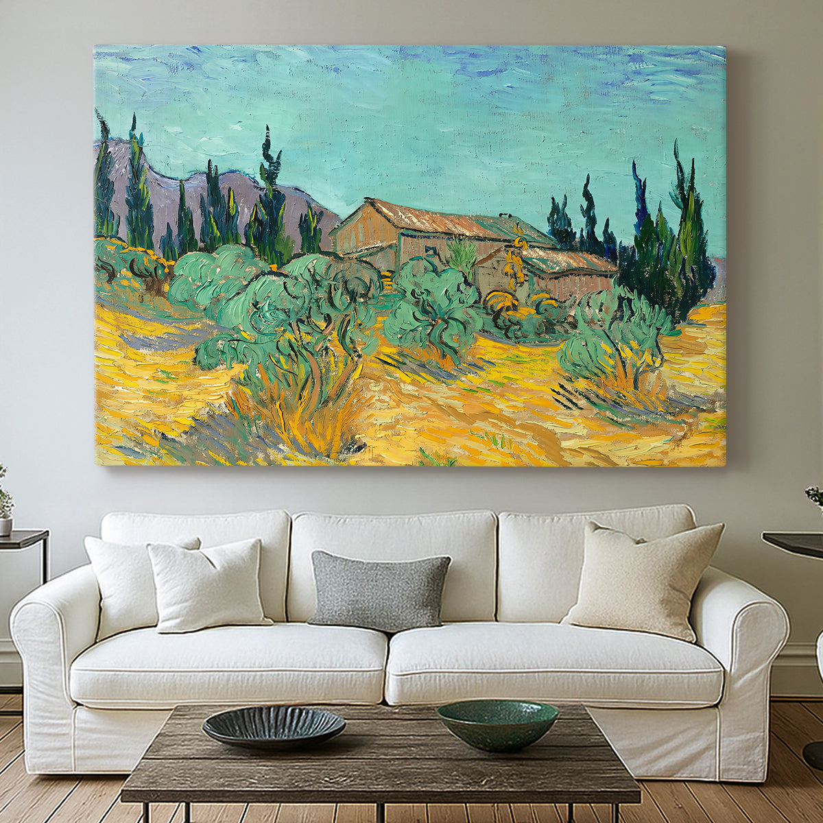 Canvas art print detailing a stylized rural setting with trees and structures, centered above a sofa as a large focal wall piece