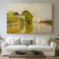 Canvas art print detailing a peaceful village scene with houses bordering water, centered above a sofa as a large focal wall piece