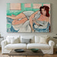 Canvas art print detailing a stylized female figure in a relaxed pose with drapery, centered above a sofa as a large focal wall piece