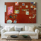 Canvas art print detailing a stylized artist studio dominated by red, centered above a sofa as a large focal wall piece