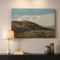 Canvas art print detailing a peaceful rural vista with greenery, water, and architectural landmark, mounted in a softly lit interior space
