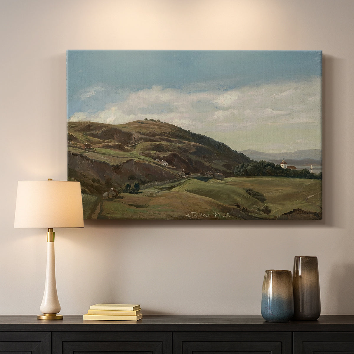 Canvas art print detailing a peaceful rural vista with greenery, water, and architectural landmark, mounted in a softly lit interior space