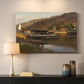 Canvas art print detailing a tranquil harbor landscape with nautical activity, mounted in a softly lit interior space