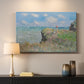 Canvas art print detailing an elevated shoreline path with figures and bright sky, mounted in a softly lit interior space