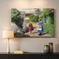 Canvas art print detailing a peaceful summer day with figures in small town environment, mounted in a softly lit interior space