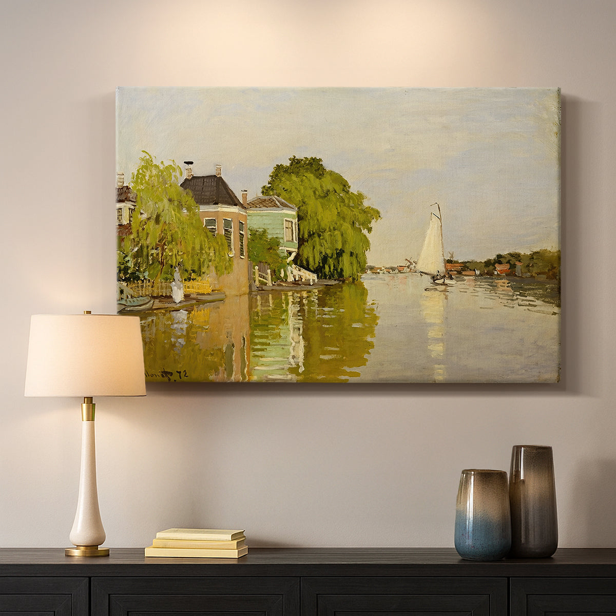 Canvas art print detailing a peaceful village scene with houses bordering water, mounted in a softly lit interior space