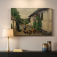 Canvas art print detailing a countryside visit scene with figures in front of rustic buildings, mounted in a softly lit interior space