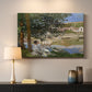 Canvas art print detailing a quiet outdoor setting with figures near river under foliage, mounted in a softly lit interior space