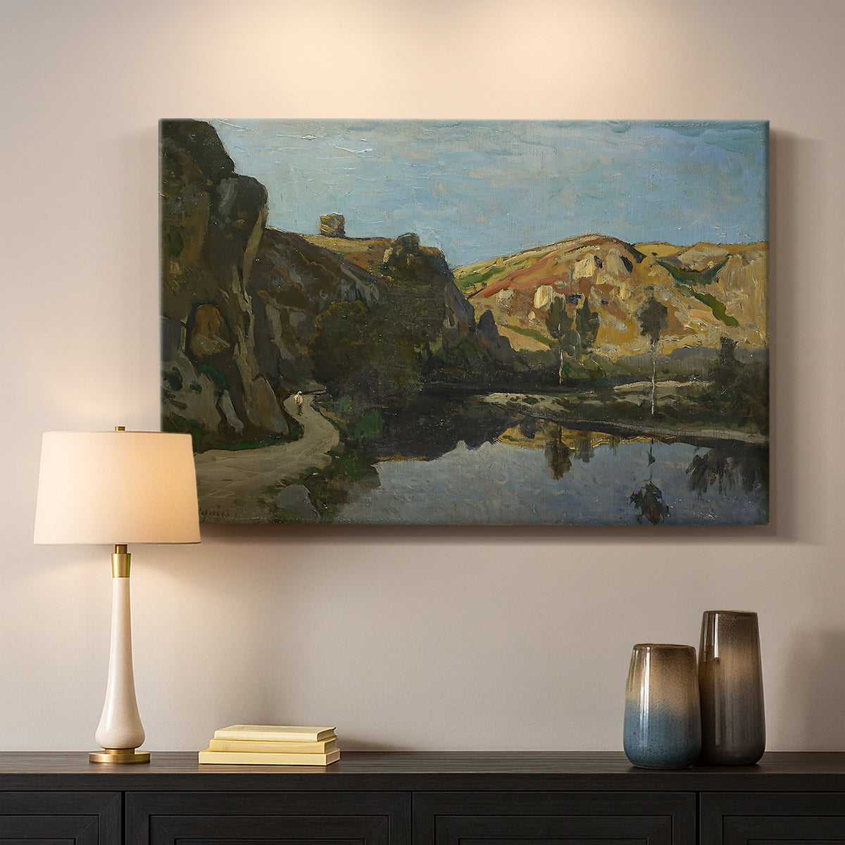 Canvas art print detailing a pastoral setting with water cutting through rugged terrain, mounted in a softly lit interior space