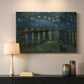 Canvas art print detailing a nocturnal landscape emphasizing contrast between lights and dark water, mounted in a softly lit interior space