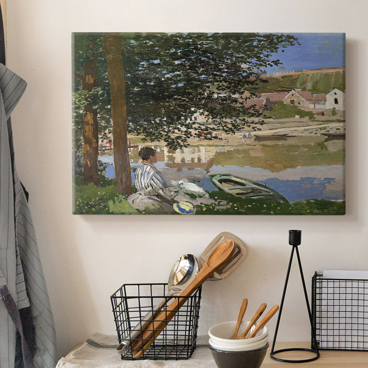 Canvas art print detailing a quiet outdoor setting with figures near river under foliage, displayed in a softly lit workspace setting