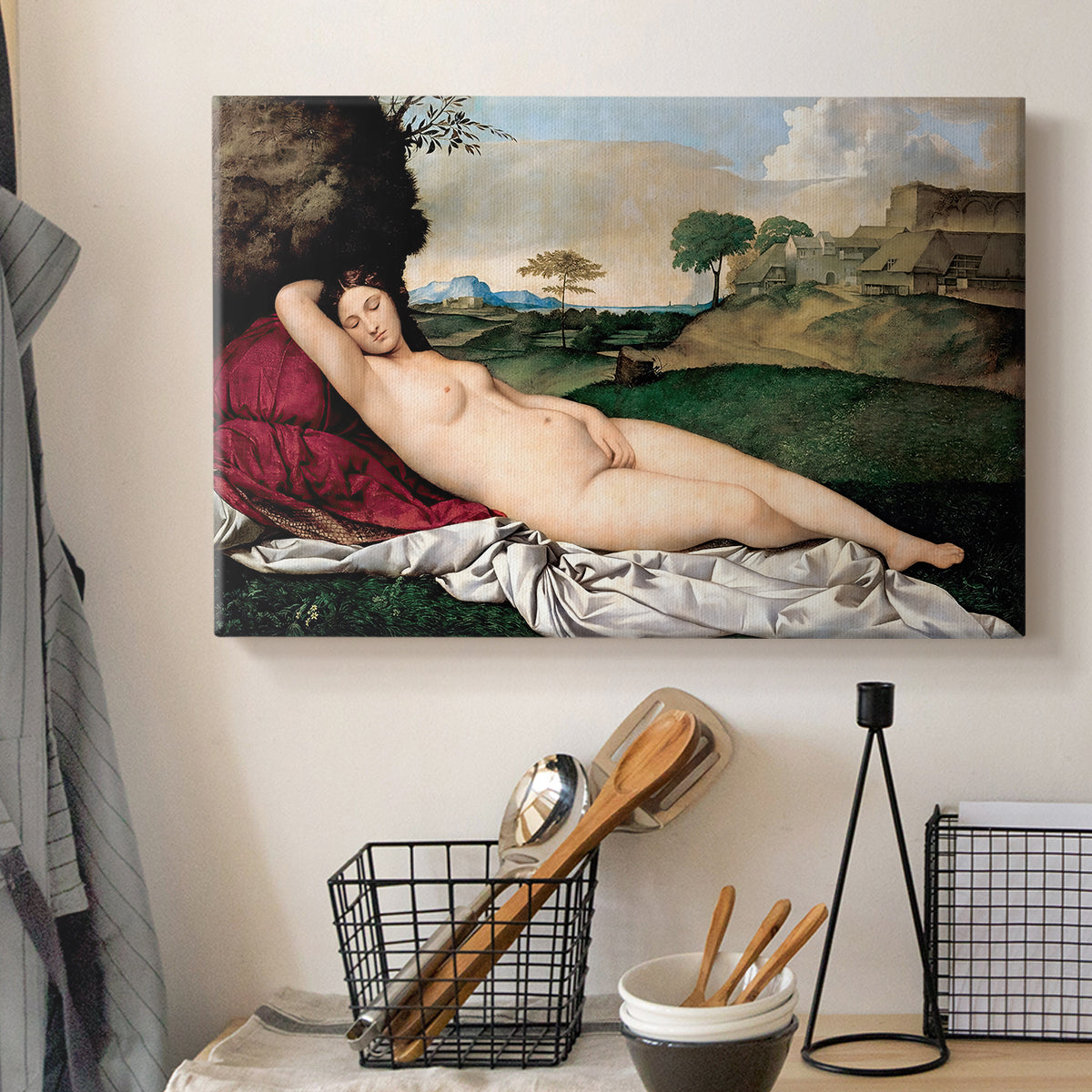 Canvas art print detailing a classical reclining nude surrounded by gentle landscape, displayed in a softly lit workspace setting