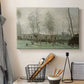 Canvas art print detailing a tranquil outdoor scene with washerwomen and foliage, displayed in a softly lit workspace setting