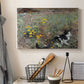 Canvas art print detailing a naturalistic depiction of cat in blooming countryside setting, displayed in a softly lit workspace setting
