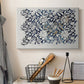 Canvas art print detailing a botanical pattern with fluid arrangement of flowers and foliage, displayed in a softly lit workspace setting