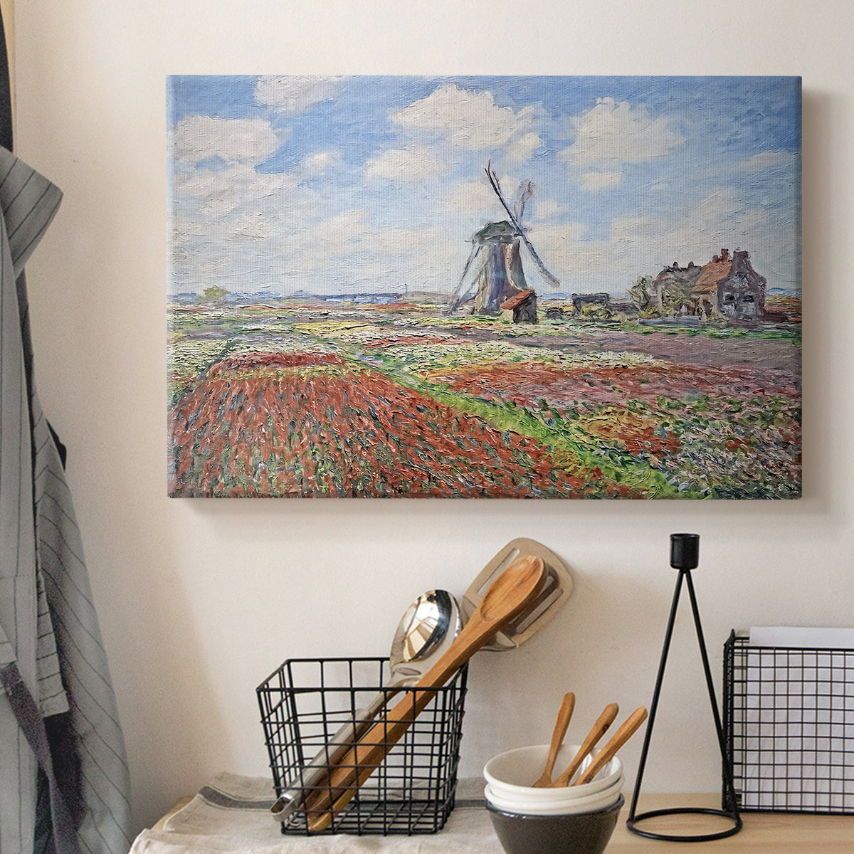 Canvas art print detailing a rural scene with patterned rows of flowers and windmill, displayed in a softly lit workspace setting