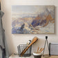 Canvas art print detailing a rugged mountain pass scene with distant peaks, displayed in a softly lit workspace setting