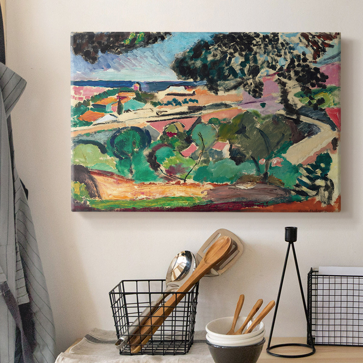 Canvas art print detailing a stylized coastal landscape with buildings and trees, displayed in a softly lit workspace setting