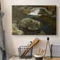 Canvas art print detailing a peaceful natural setting with mill and still water, displayed in a softly lit workspace setting